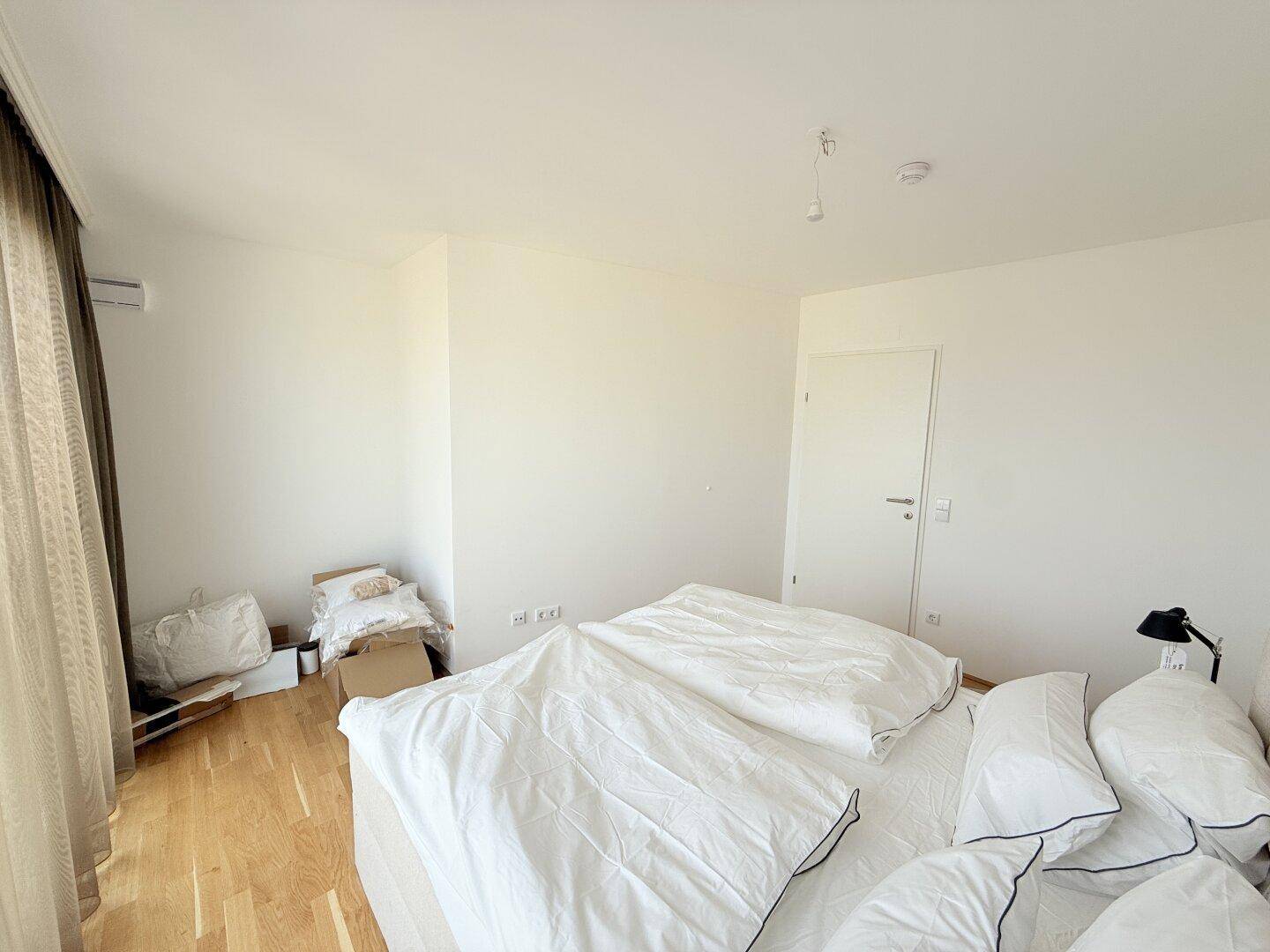 Geräumiges Schlafzimmer mit hellem Parkettboden und weiß gestrichenen Wänden.