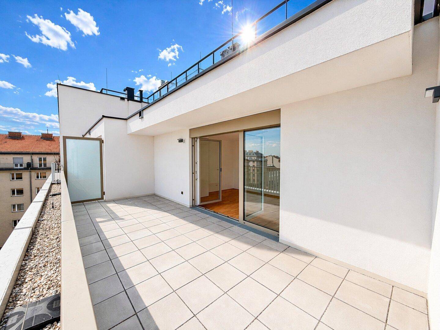 Helle Dachterrasse mit Fliesenboden und großzügigem Zugang zu den Innenräumen, ideal für Entspannung.