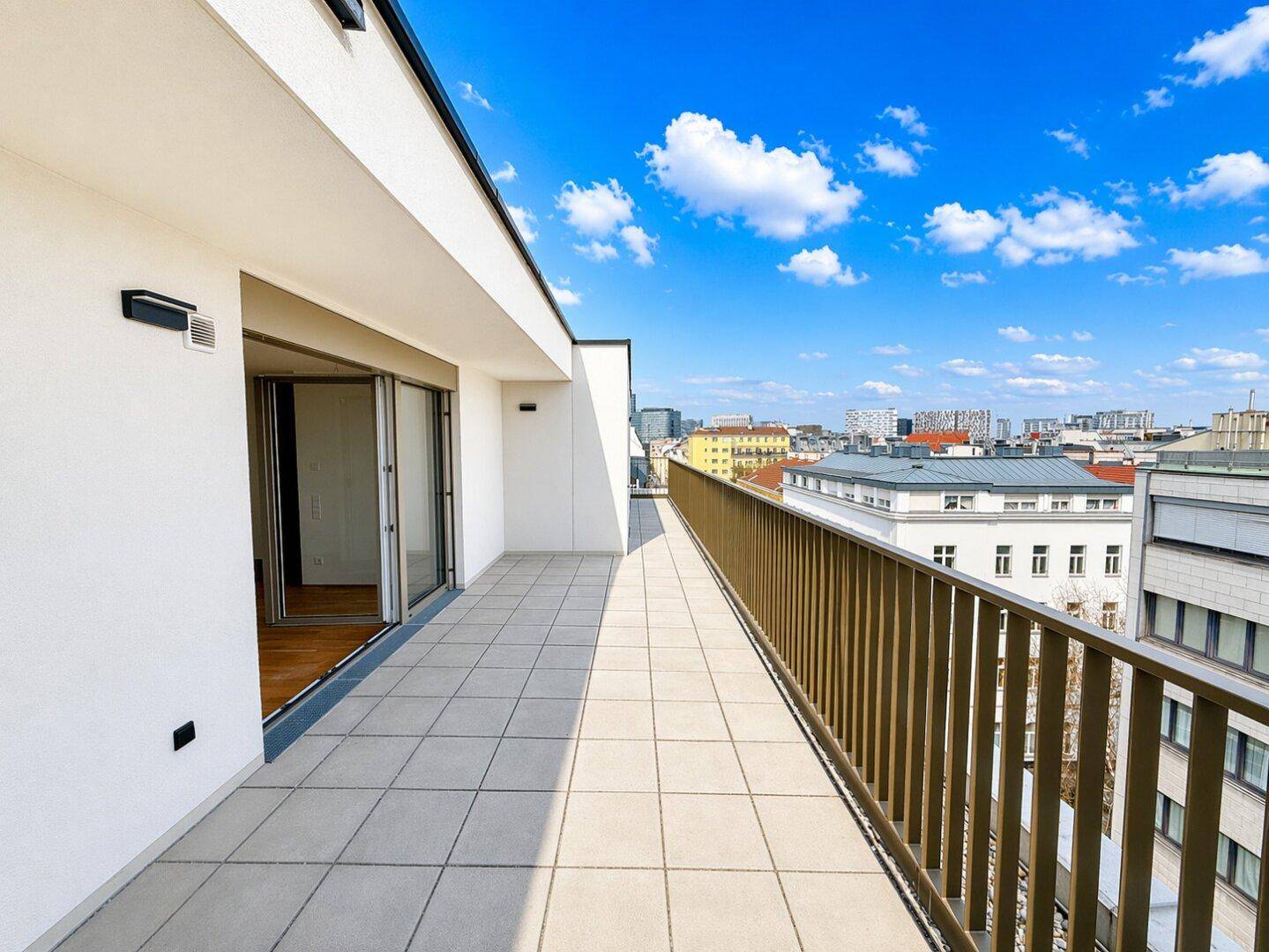 Weitläufige Dachterrasse mit Fliesenboden und Schiebetüren zum Innenbereich.