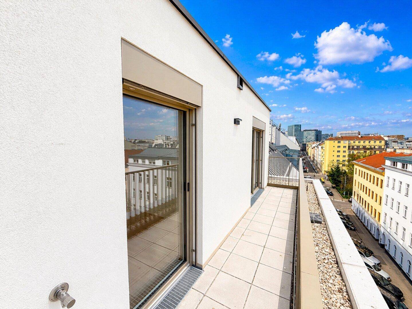 Langer Balkon mit Fliesenboden und Blick auf die umliegende Stadtstraße.