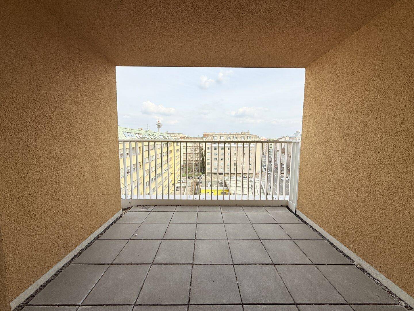 Überdachte Loggia mit Fliesenboden und Blick auf die umliegenden Gebäude der Stadt.