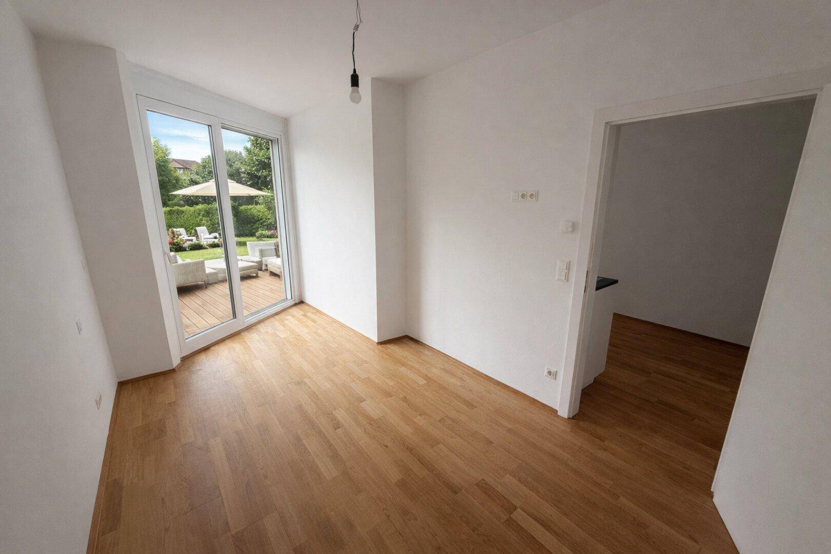 Heller Raum mit Holzboden und direktem Zugang zu einer Terrasse oder dem Garten.