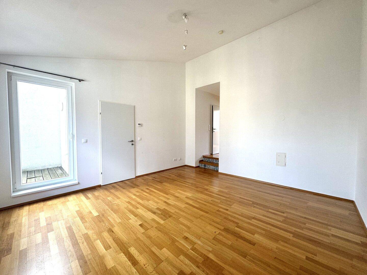 Geräumiges Zimmer mit Parkettboden und Zugang zu einem Außenbereich, ideal für helle Wohnkonzepte.