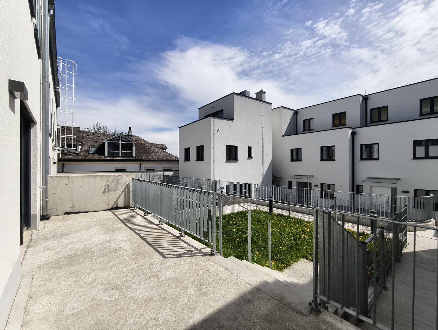 Große unmöblierte Terrasse mit Metallgeländer und Blick auf die Nachbarschaft.