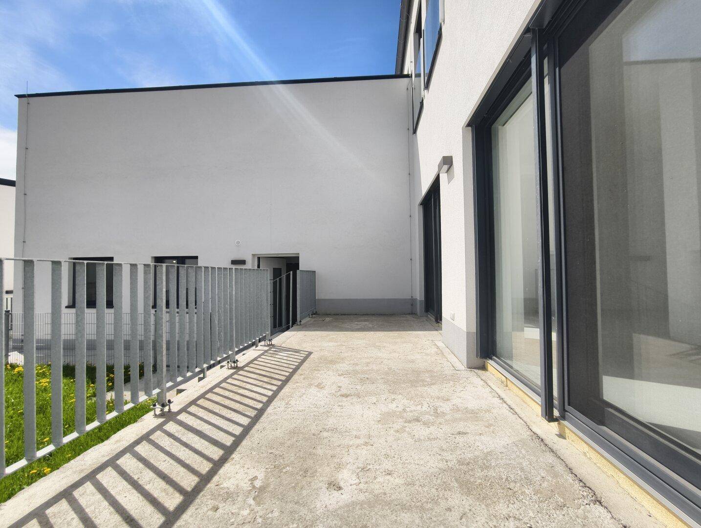 Unmöblierte Terrasse mit Betonboden und Blick auf die umliegenden Gebäude.