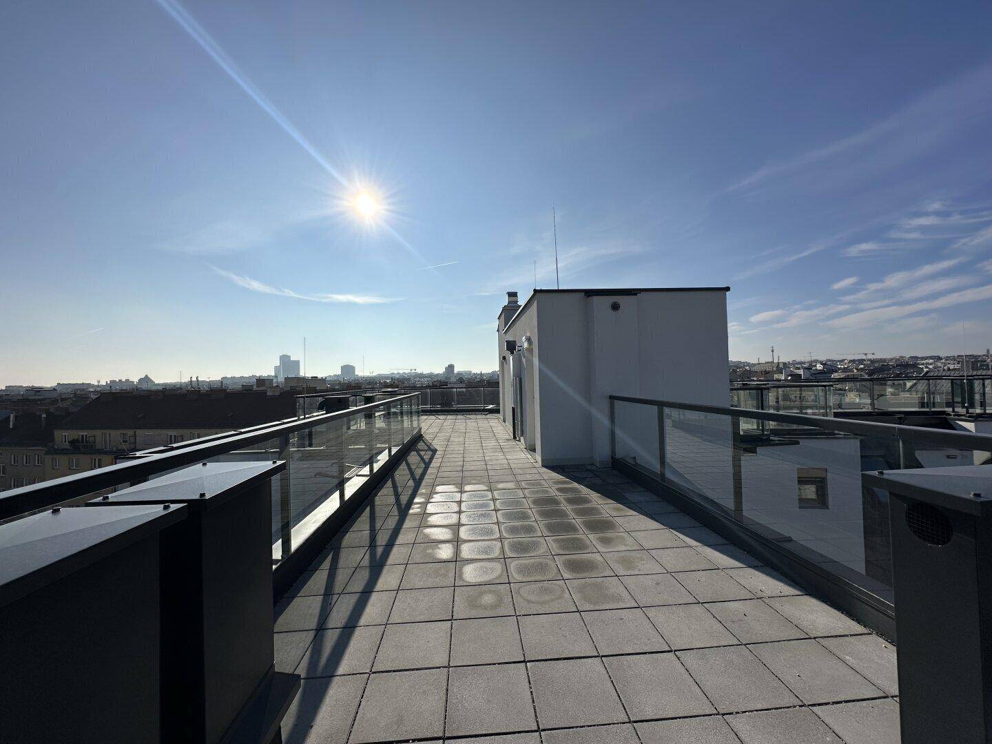 Sonnige Dachterrasse mit modernem Design und weitem Blick über die städtische Skyline.