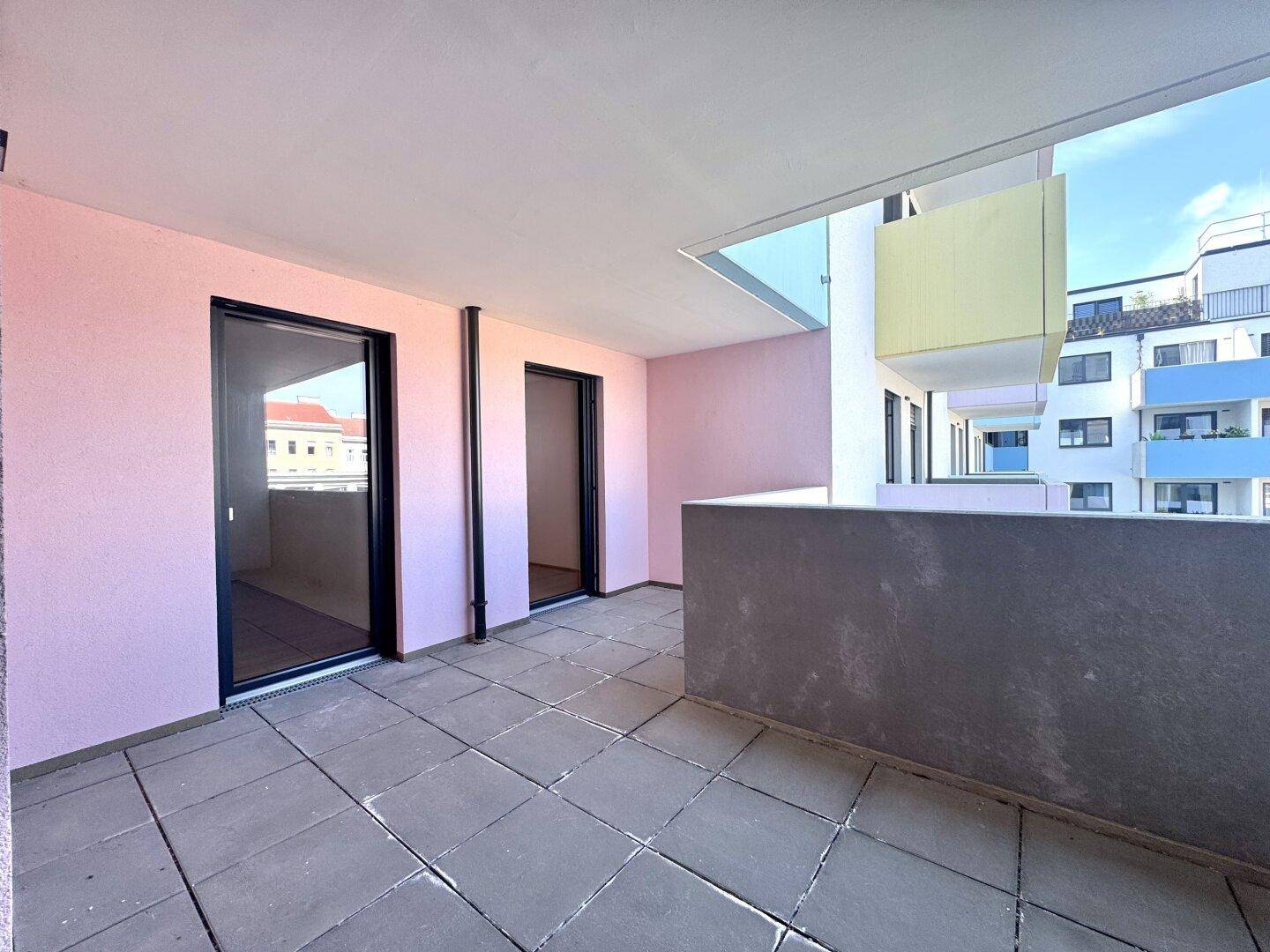 Geräumiger Balkon mit Fliesenboden und rosa gestrichenen Wänden, ideal für Entspannung im Freien.