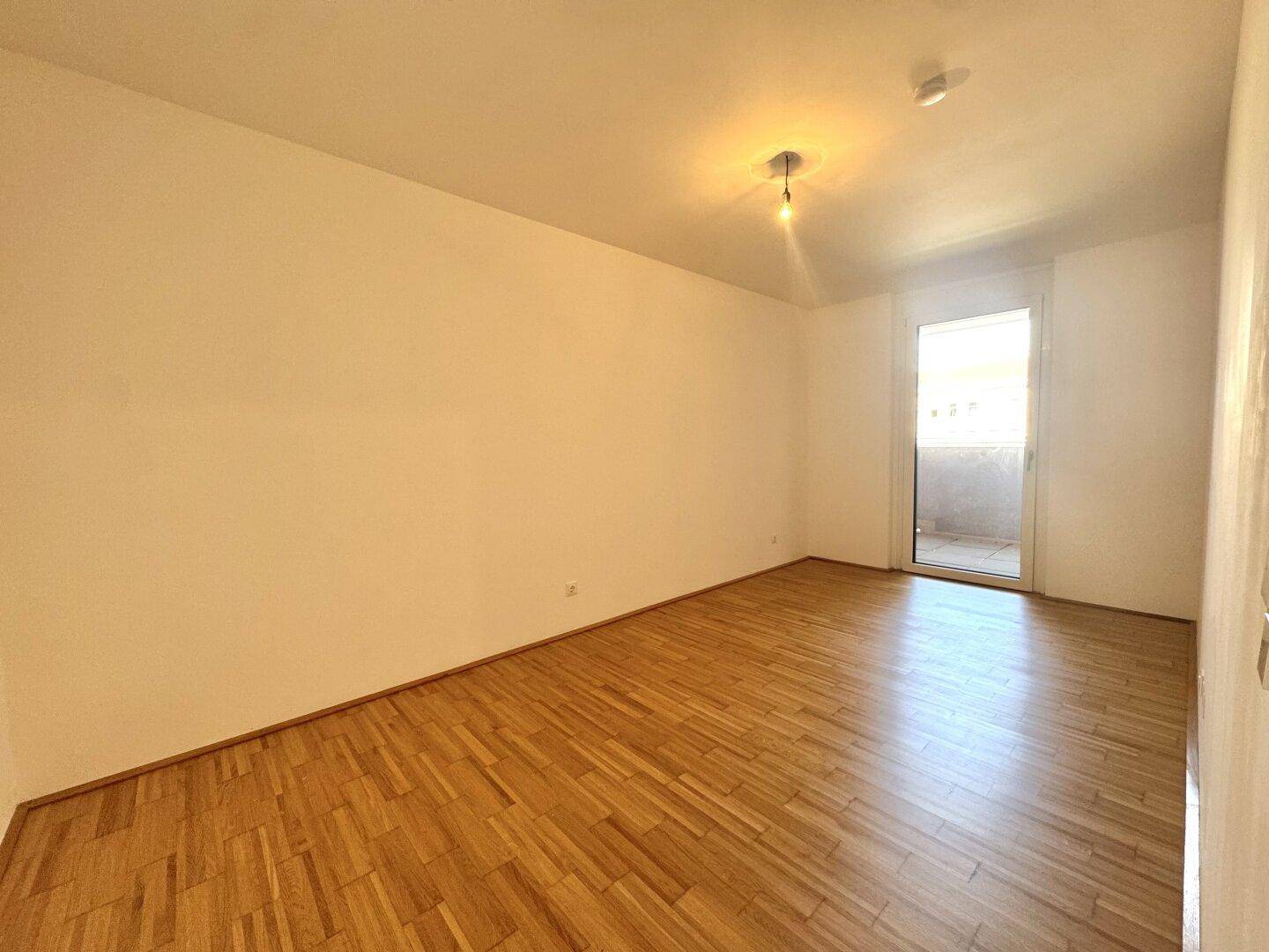 Helles Schlafzimmer mit Parkettboden und direktem Zugang zu einem Außenbereich.