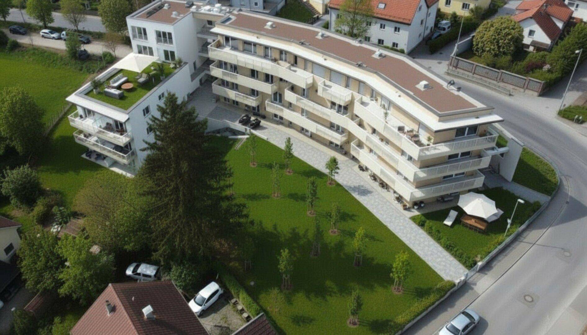 Luftaufnahme eines modernen Wohnkomplexes mit weitläufigen Grünflächen und umliegender Bebauung.