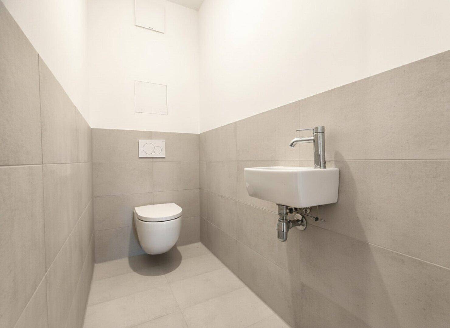 Kleines Gäste-WC mit Wand-WC und Handwaschbecken in modernem Design.