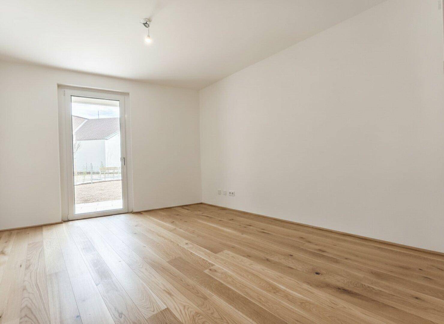 Helles Schlafzimmer mit Holzdielenboden und direktem Zugang zu einem kleinen Außenbereich.