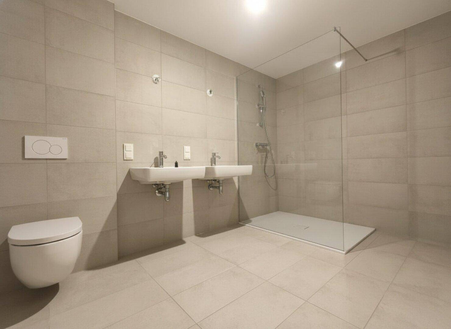 Modernes Badezimmer mit hellgrauen Fliesen, Doppelwaschbecken und ebenerdiger Dusche.