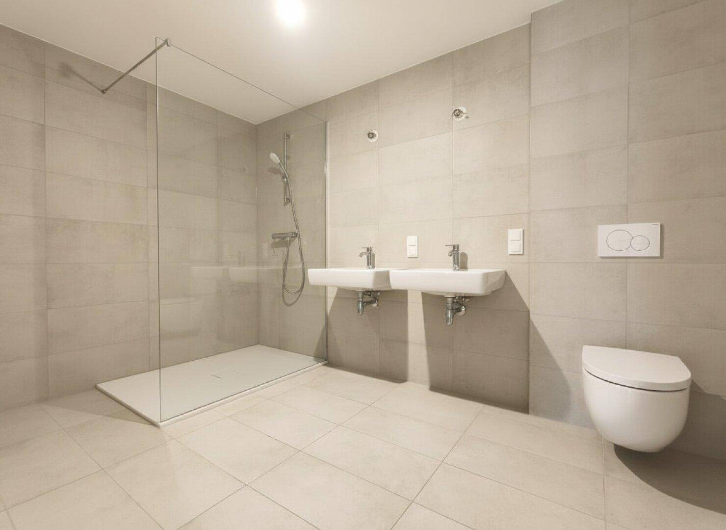 Modernes Badezimmer mit grauen Fliesen, Doppelwaschbecken und ebenerdiger Dusche.