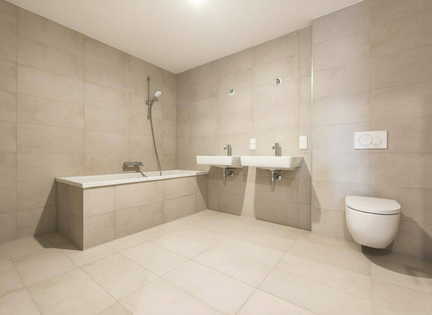 Modernes Badezimmer mit beigefarbenen Fliesen, Badewanne, Doppelwaschbecken und wandhängendem WC.