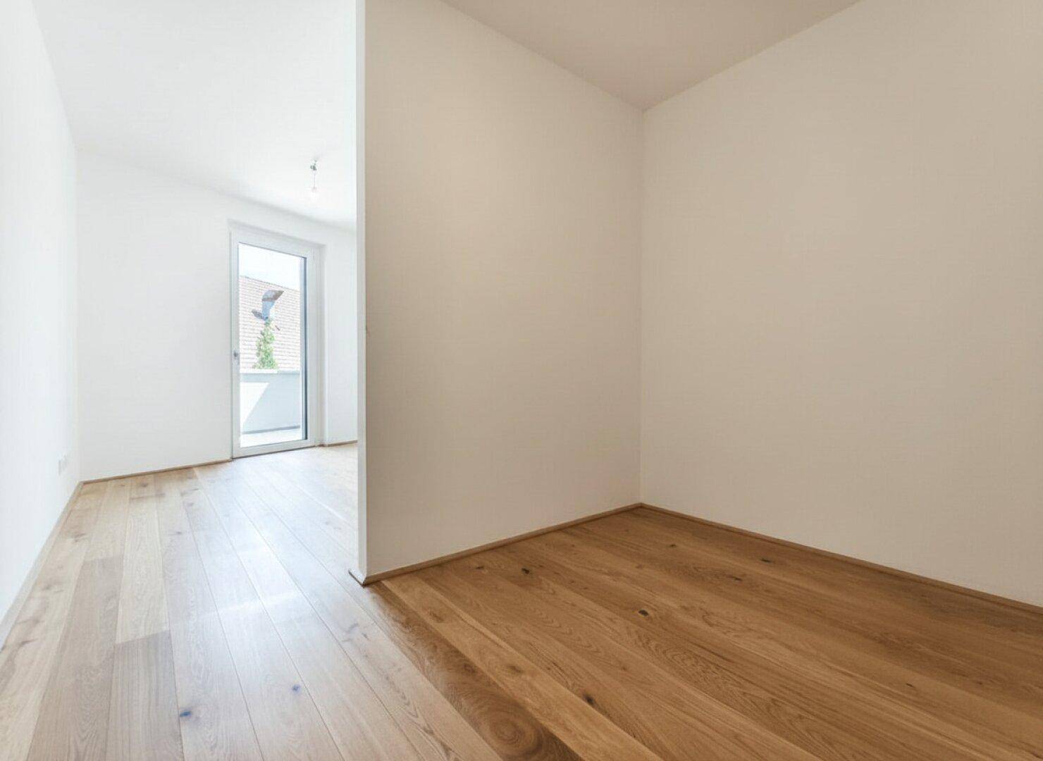 Heller Raum mit Holzboden und weiß gestrichenen Wänden, bietet flexible Nutzungsmöglichkeiten.