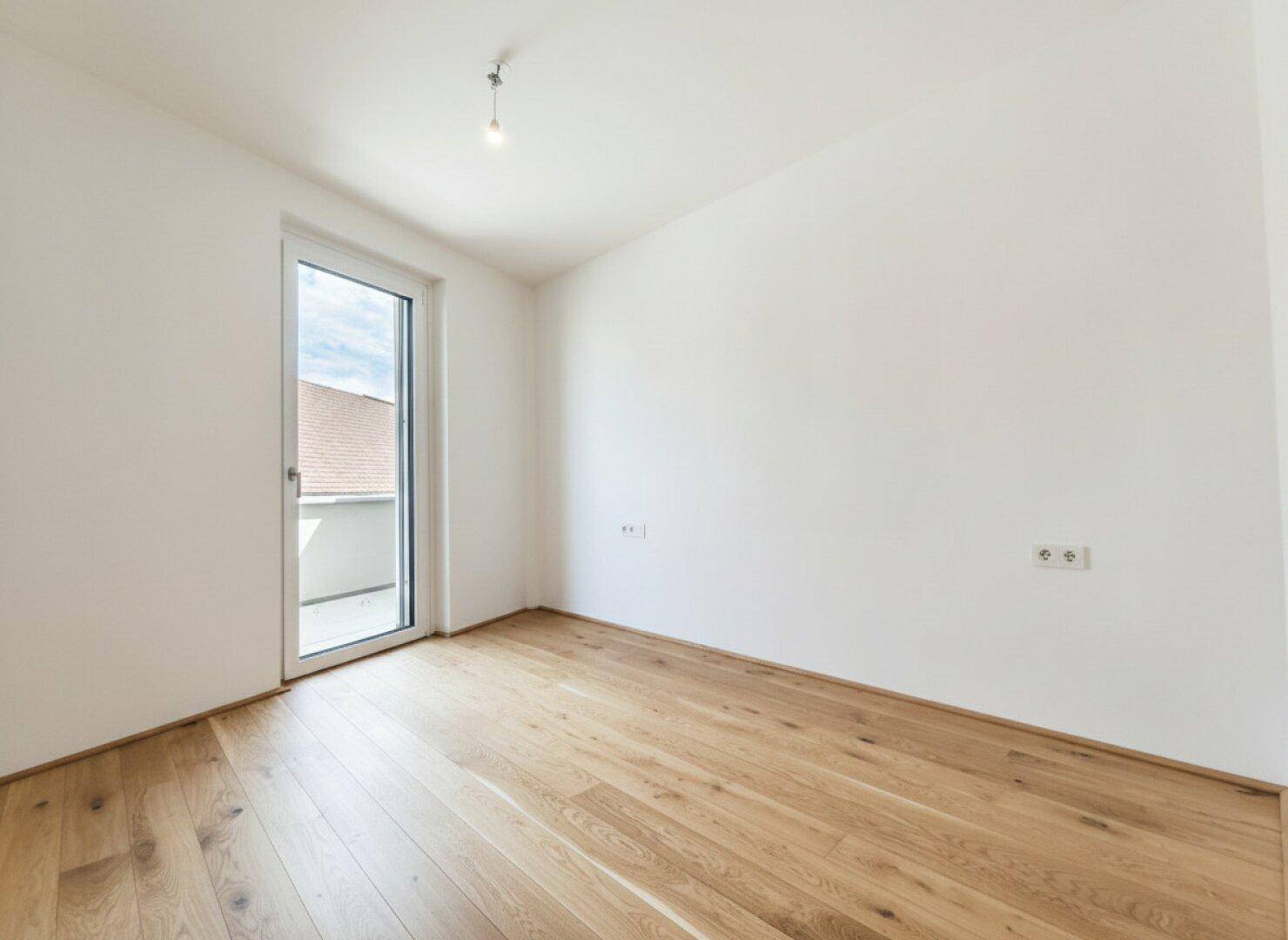 Ruhiges Schlafzimmer mit Holzboden und weiß gestrichenen Wänden, bereit für persönliche Einrichtung.
