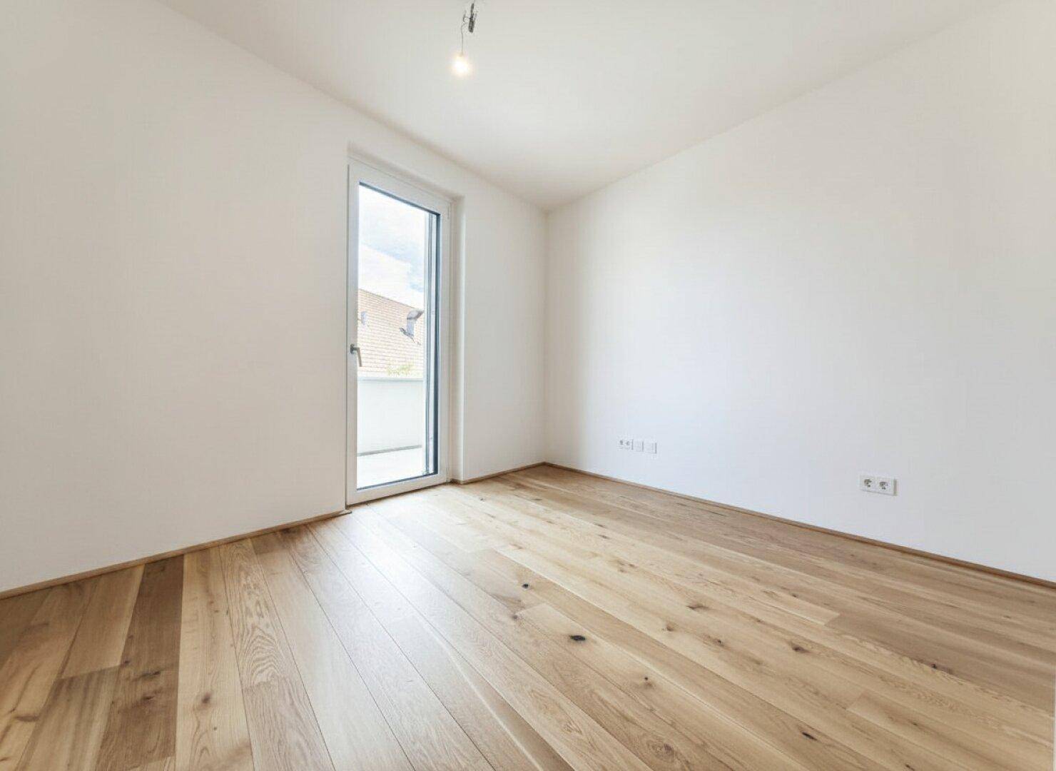 Helles Schlafzimmer mit Eichenparkett und Zugang zu einem französischen Balkon, ideal für Ruhe.