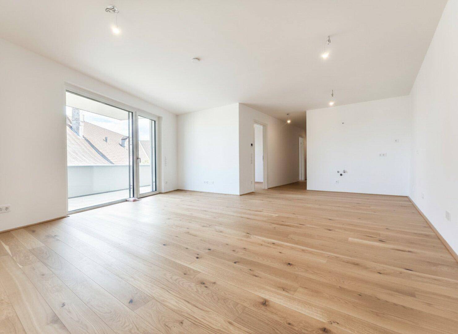 Heller, leerer Raum mit Eichenparkett und Zugang zu einem Balkon, ideal für Wohn- oder Schlafzimmer.