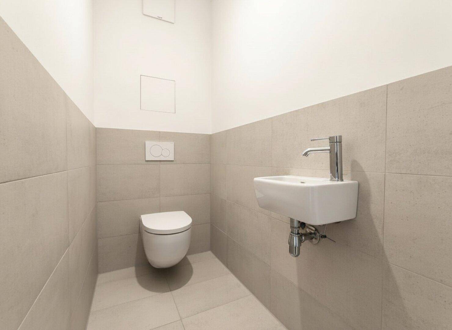 Modernes Gäste-WC mit wandhängender Toilette und kleinem Waschbecken.