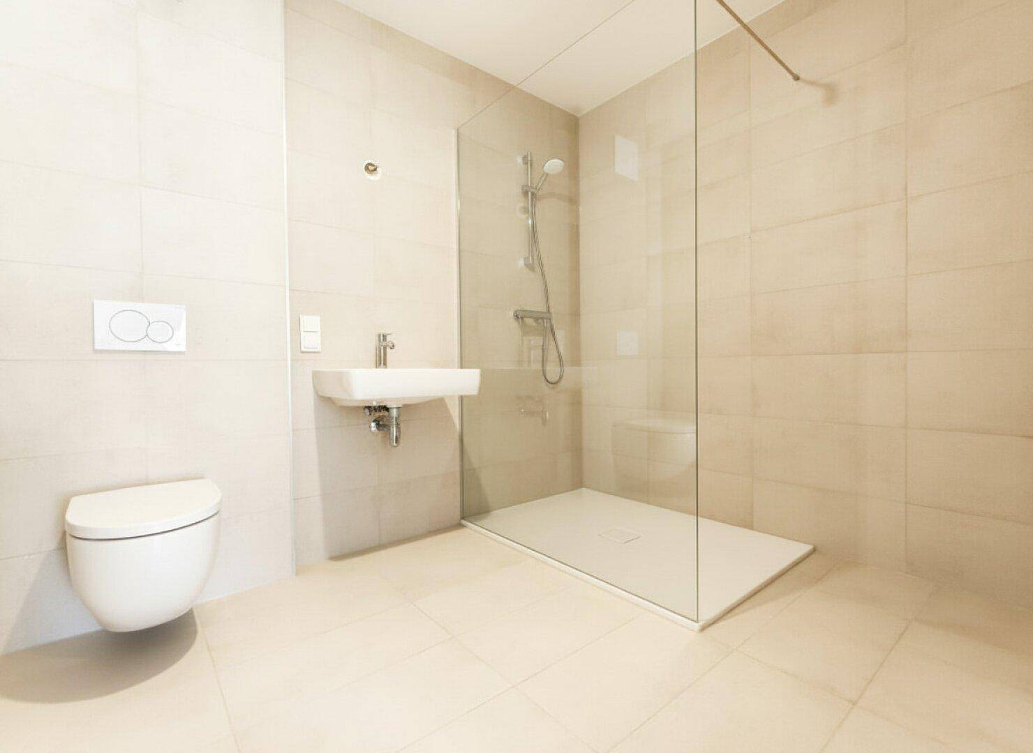 Modernes Badezimmer mit bodengleicher Dusche, wandhängendem WC und hellem Fliesenboden.