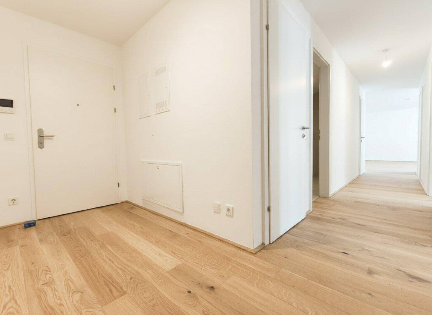 Heller Flur mit Holzboden und mehreren weißen Türen, der zu verschiedenen Räumen führt.
