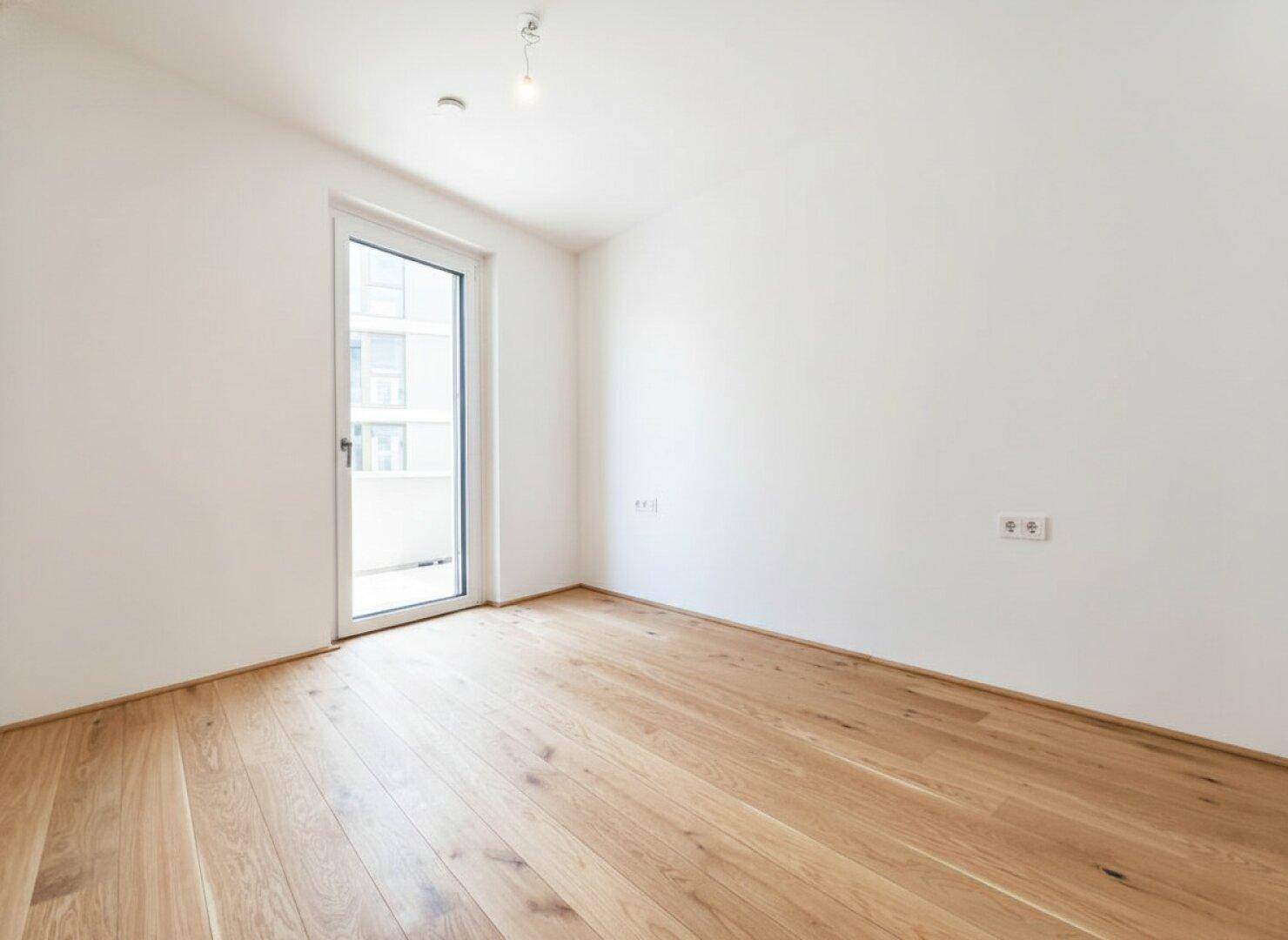 Geräumiges Schlafzimmer mit Holzboden und direktem Zugang zu einem privaten Balkon.
