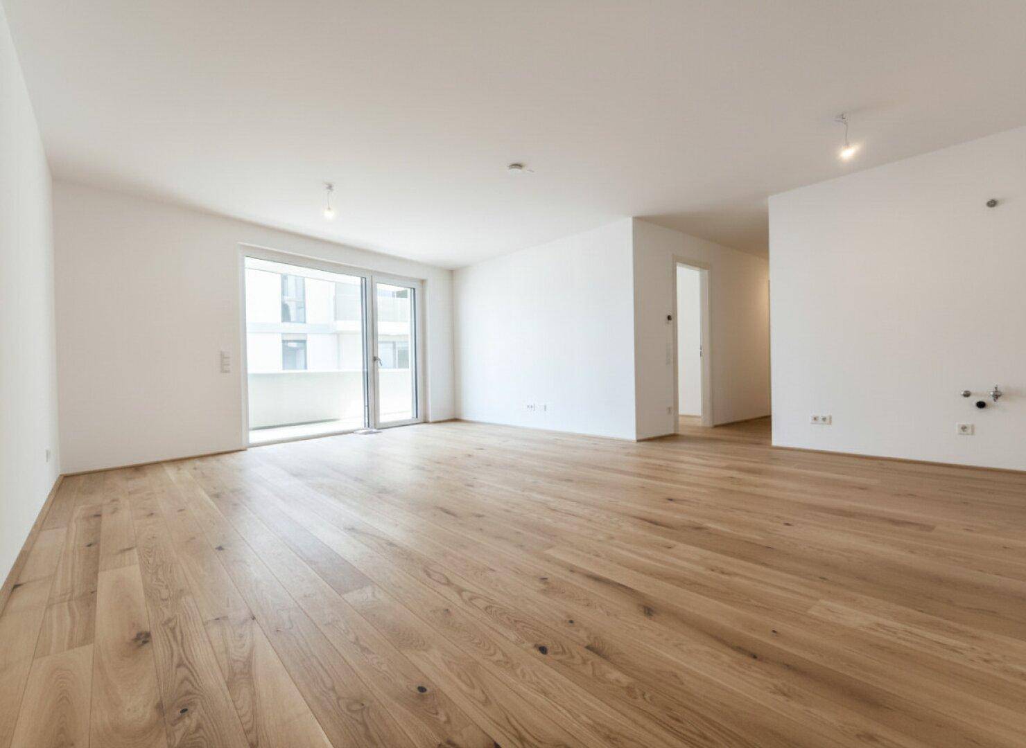 Lichtdurchfluteter Wohnbereich mit elegantem Holzboden und breiter Schiebetür zum Außenbereich.