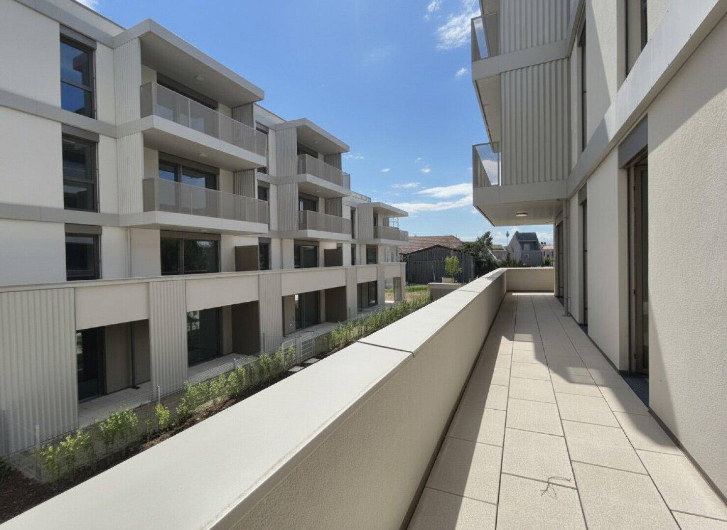 Geräumiger Balkon mit Fliesenboden und Blick auf die moderne Architektur des Gebäudes.