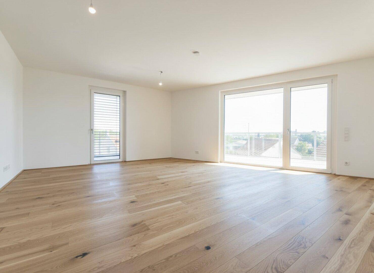 Helles, leeres Wohnzimmer mit breiten Eichenparkettdielen und Zugang zum Balkon.