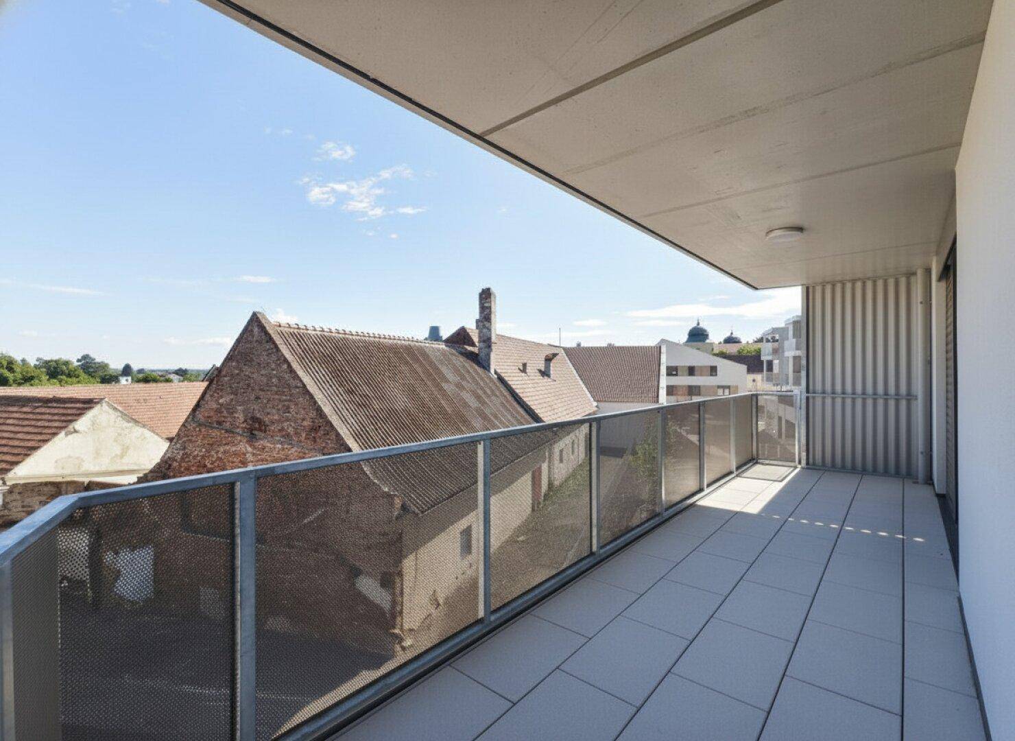Moderner Balkon mit Fliesenboden und Blick auf die umliegenden Dächer und Gebäude.