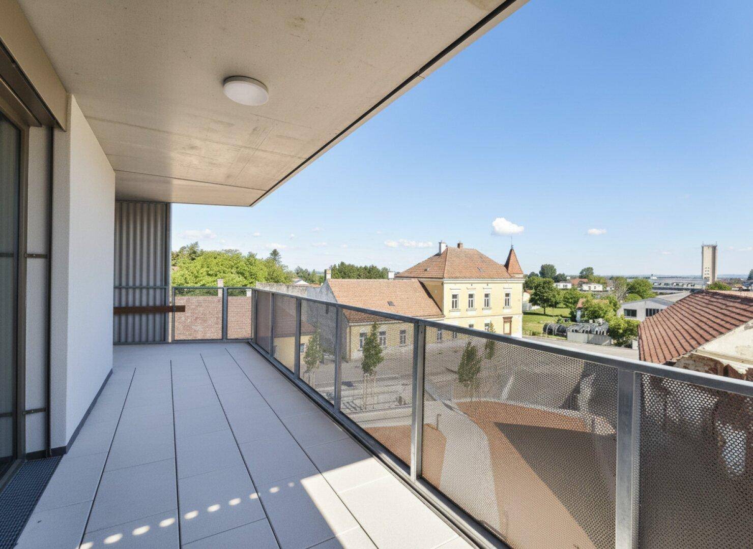 Geräumiger Balkon mit Fliesenboden und weitem Blick über die Dächer der Stadt.