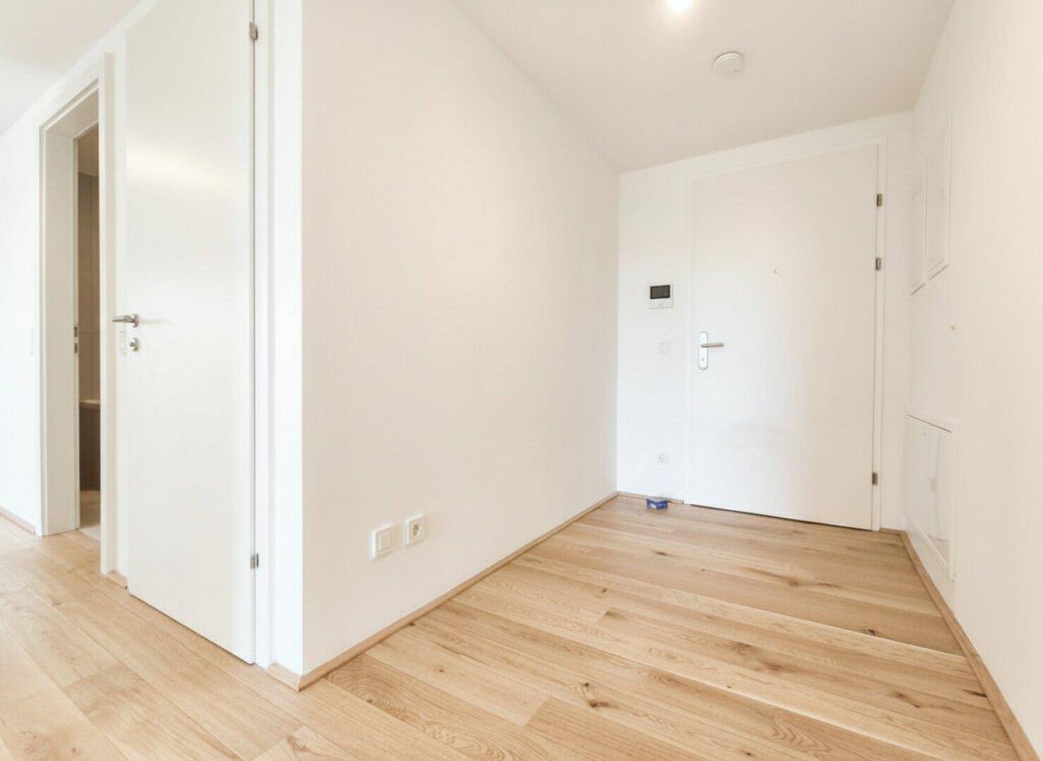 Heller Eingangsbereich mit Holzboden und weiß gestrichenen Wänden.