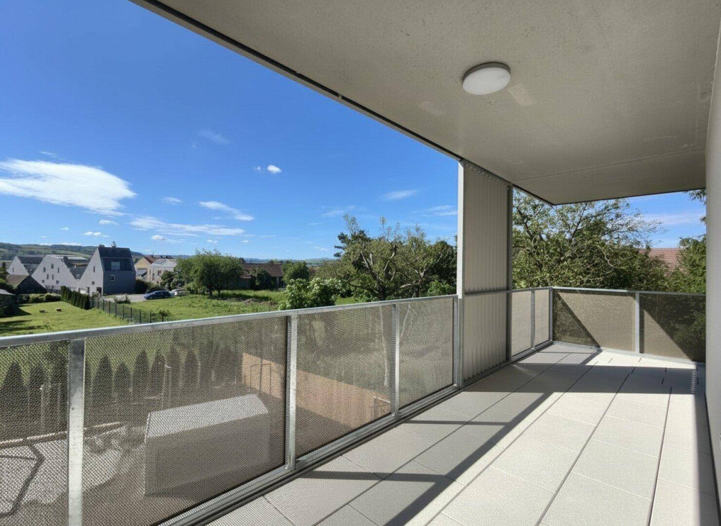 Heller Balkon mit moderner Metallbrüstung und Panoramablick über die Landschaft.