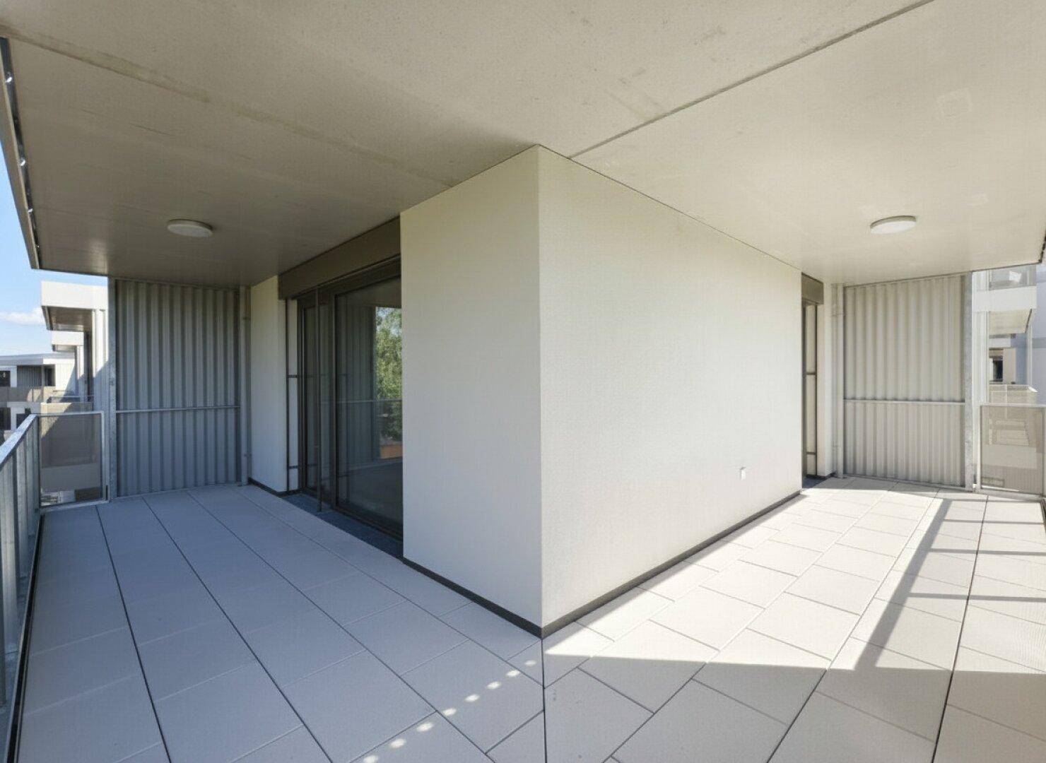 Moderner Eckbalkon mit Fliesenboden und viel Platz für Outdoor-Möbel.