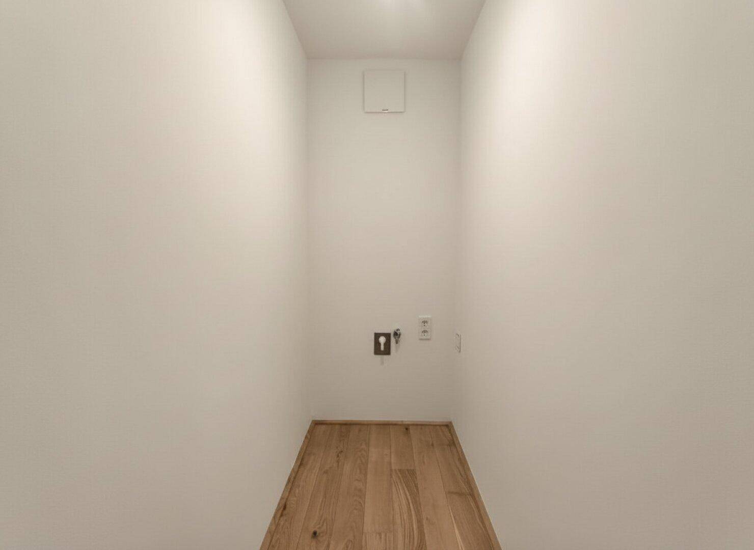 Schmaler Hauswirtschaftsraum mit Anschlüssen für Waschmaschine und Trockner, praktisch und funktional.