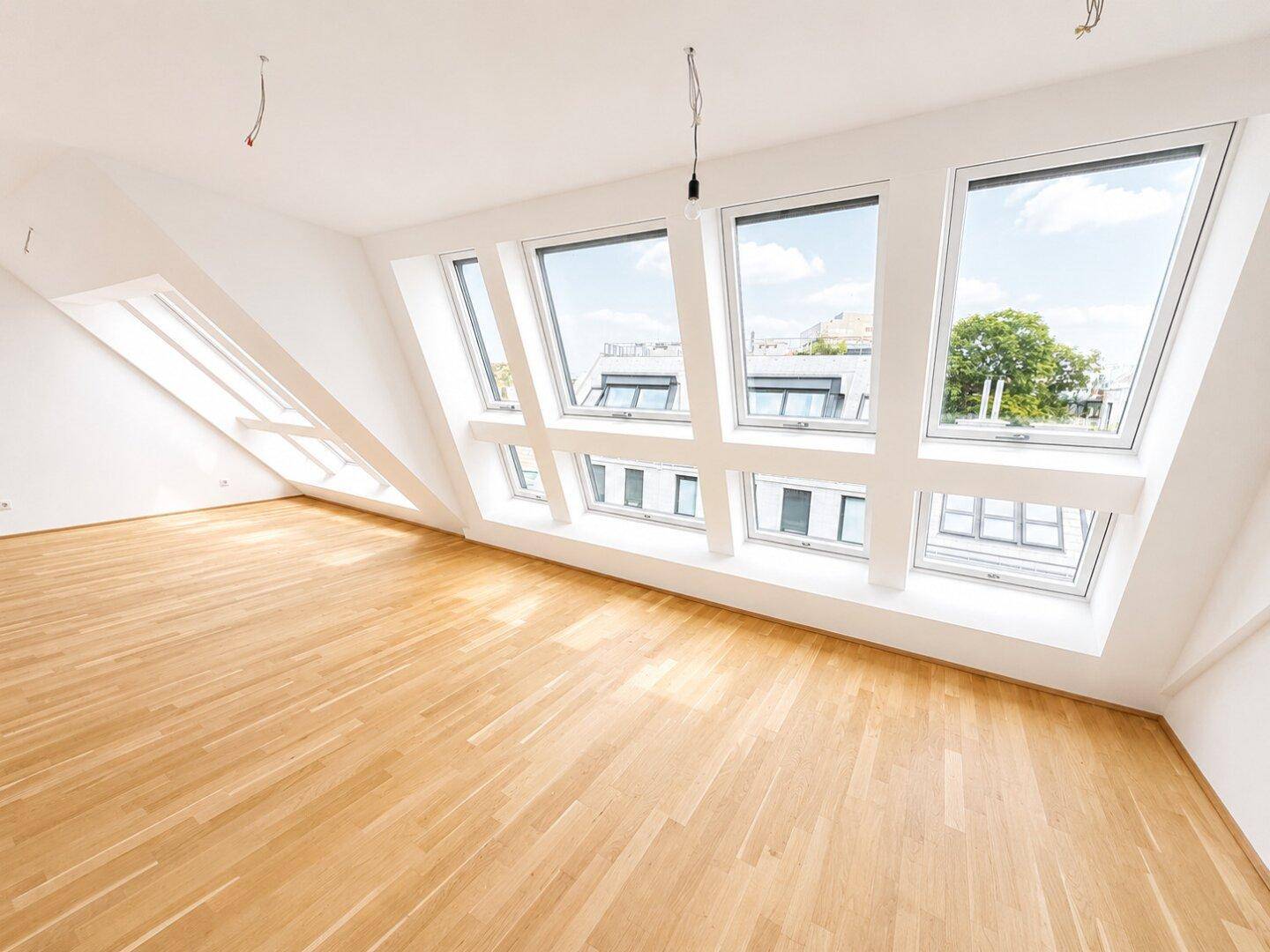 Geräumiger Dachgeschossraum mit hellem Holzboden und schrägen Wänden, ideal für individuelle Gestaltung.