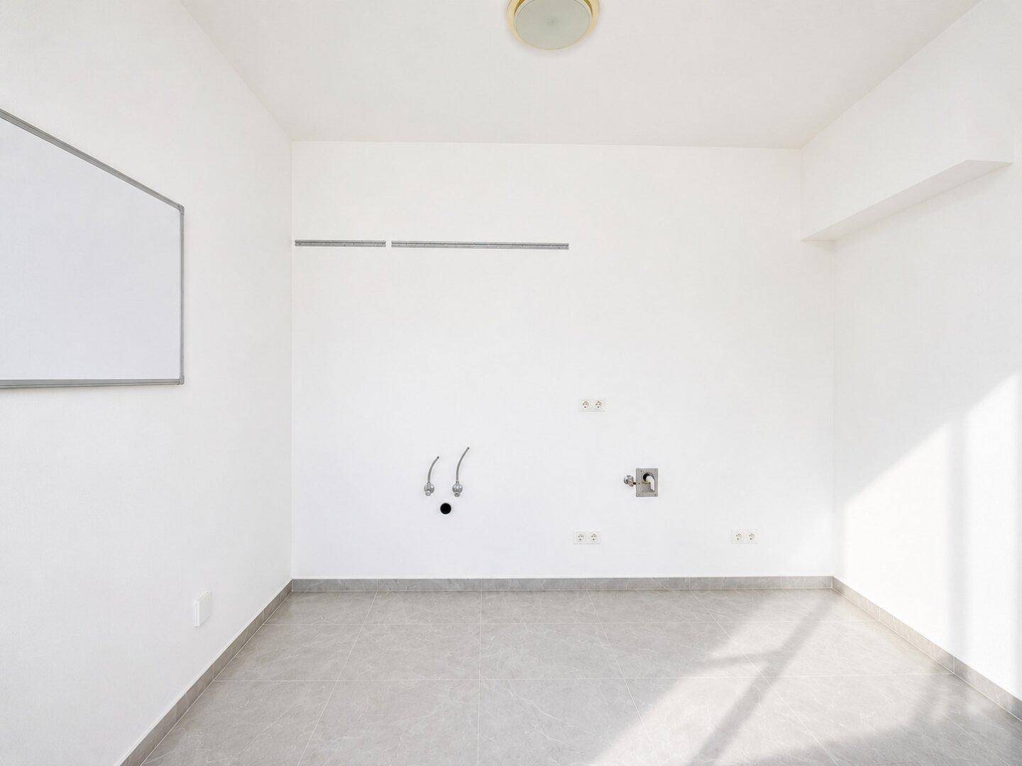 Leerer Raum mit Wandanschlüssen für Wasser und Strom, ideal für eine Küche oder einen Hauswirtschaftsraum.