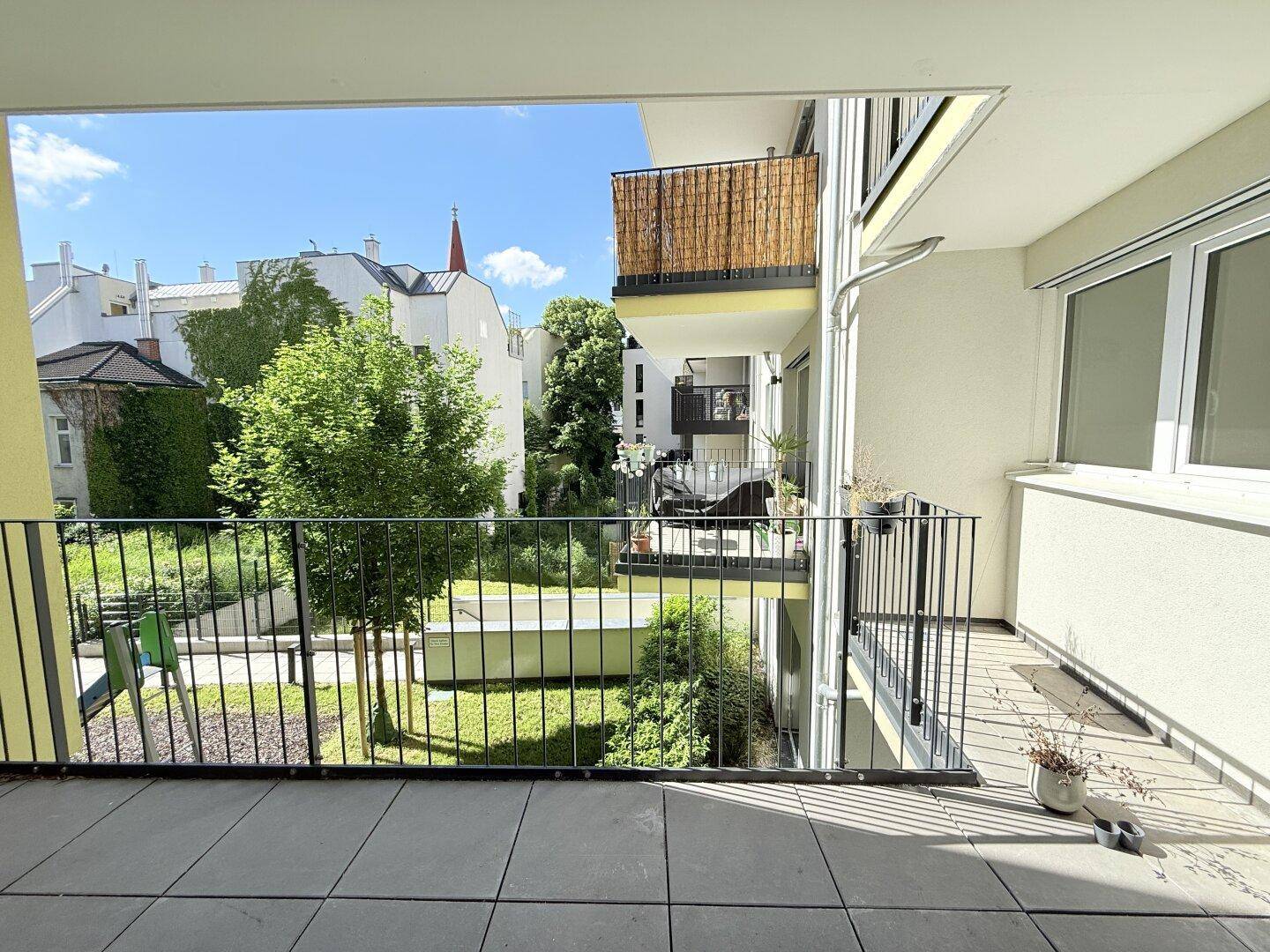 Geräumiger Balkon mit Metallgeländer und weitem Blick auf die umliegenden Gebäude und Grünflächen.