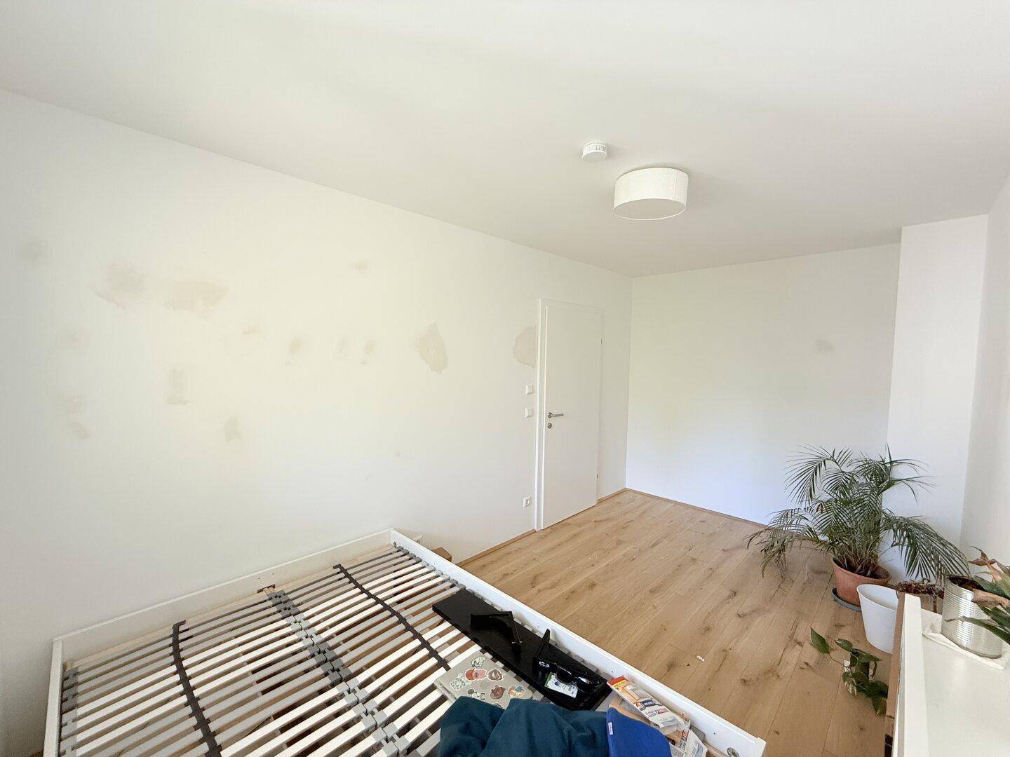 Schlafzimmer mit Parkettboden und einem Bettgestell, das auf die Einrichtung wartet.