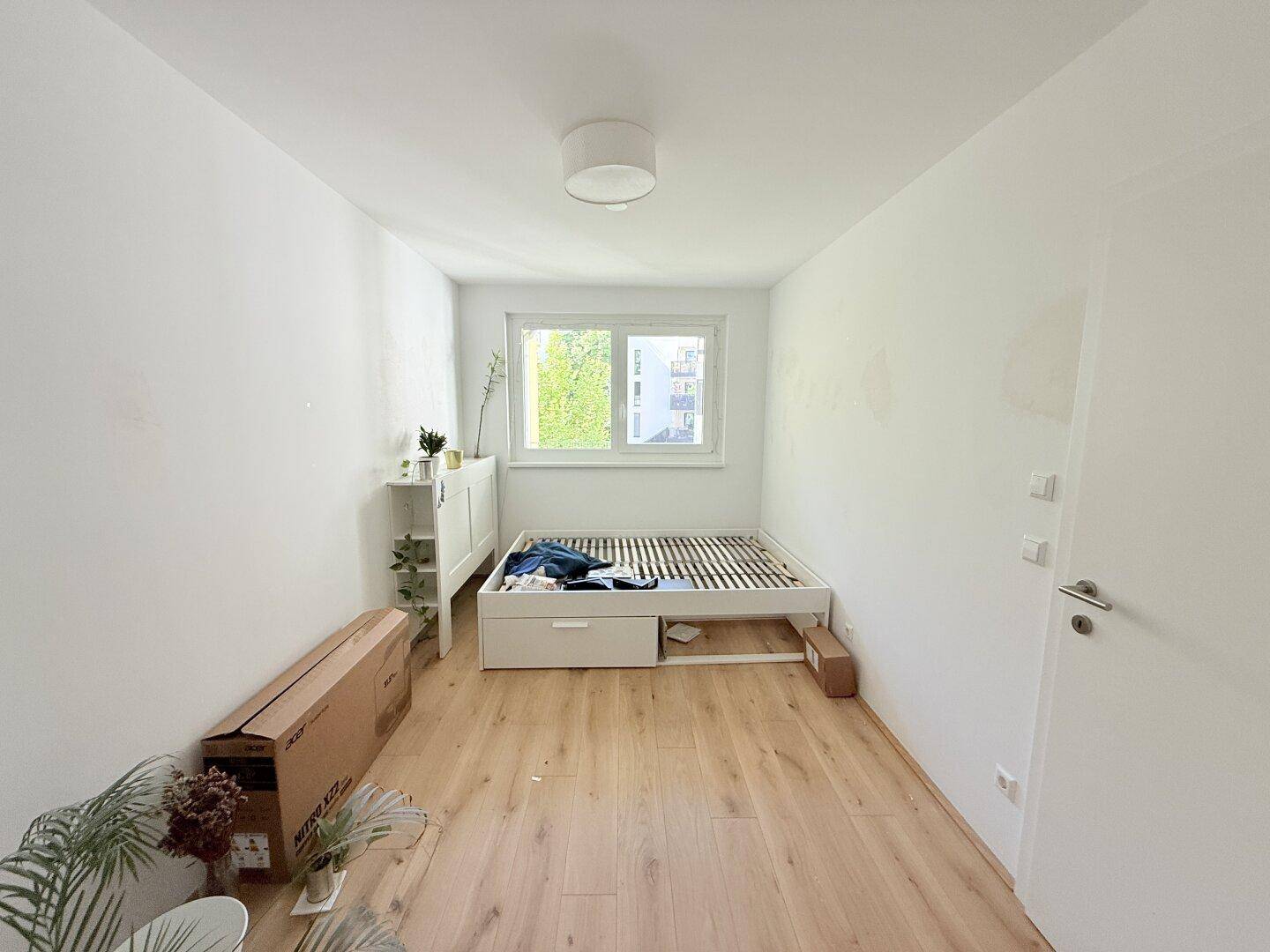 Schlafzimmer mit Parkettboden und einem Bettgestell, das auf die Einrichtung wartet.