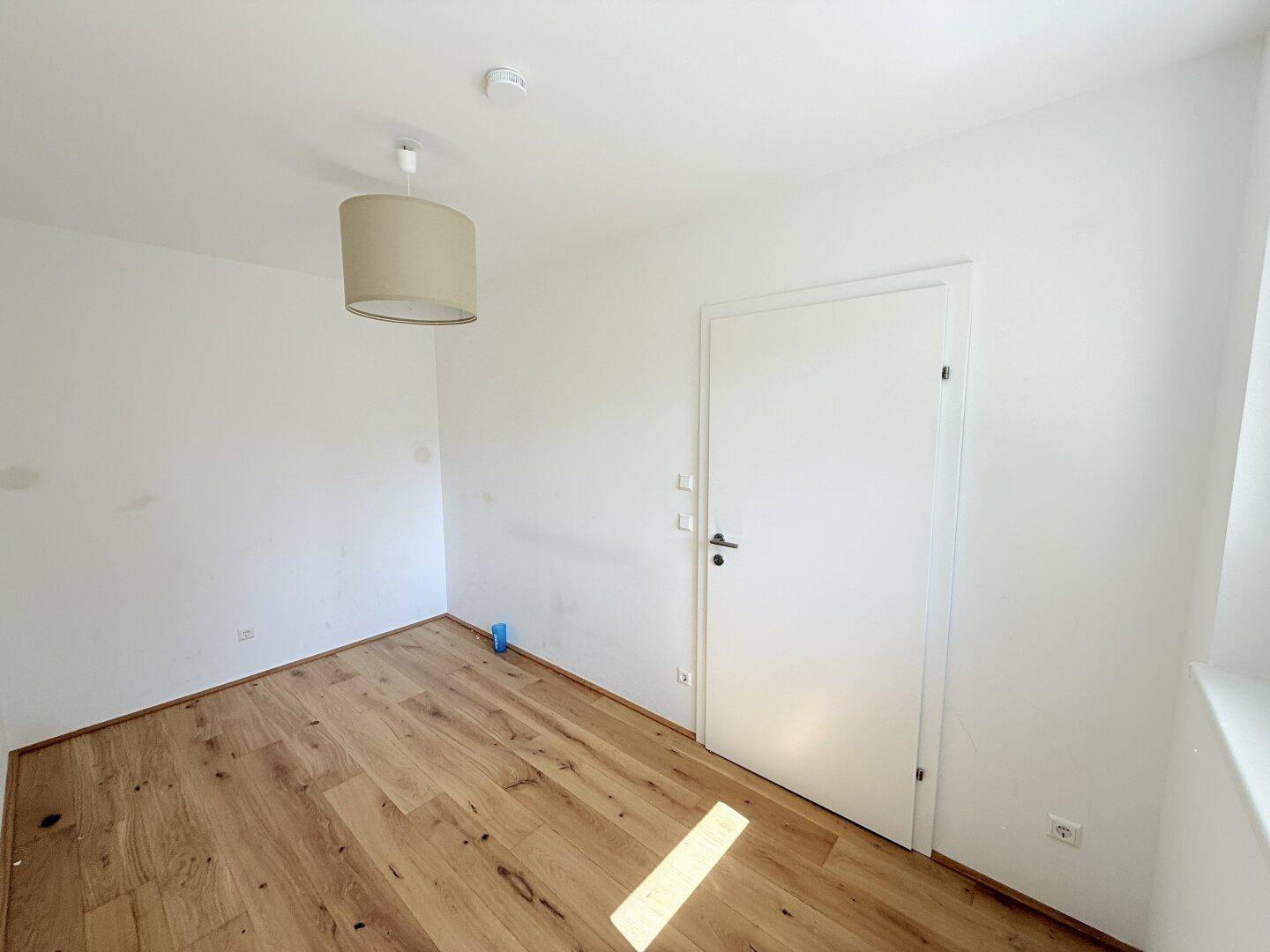 Unmöbliertes Schlafzimmer mit Parkettboden und einer weißen Tür, bereit zum Einzug.