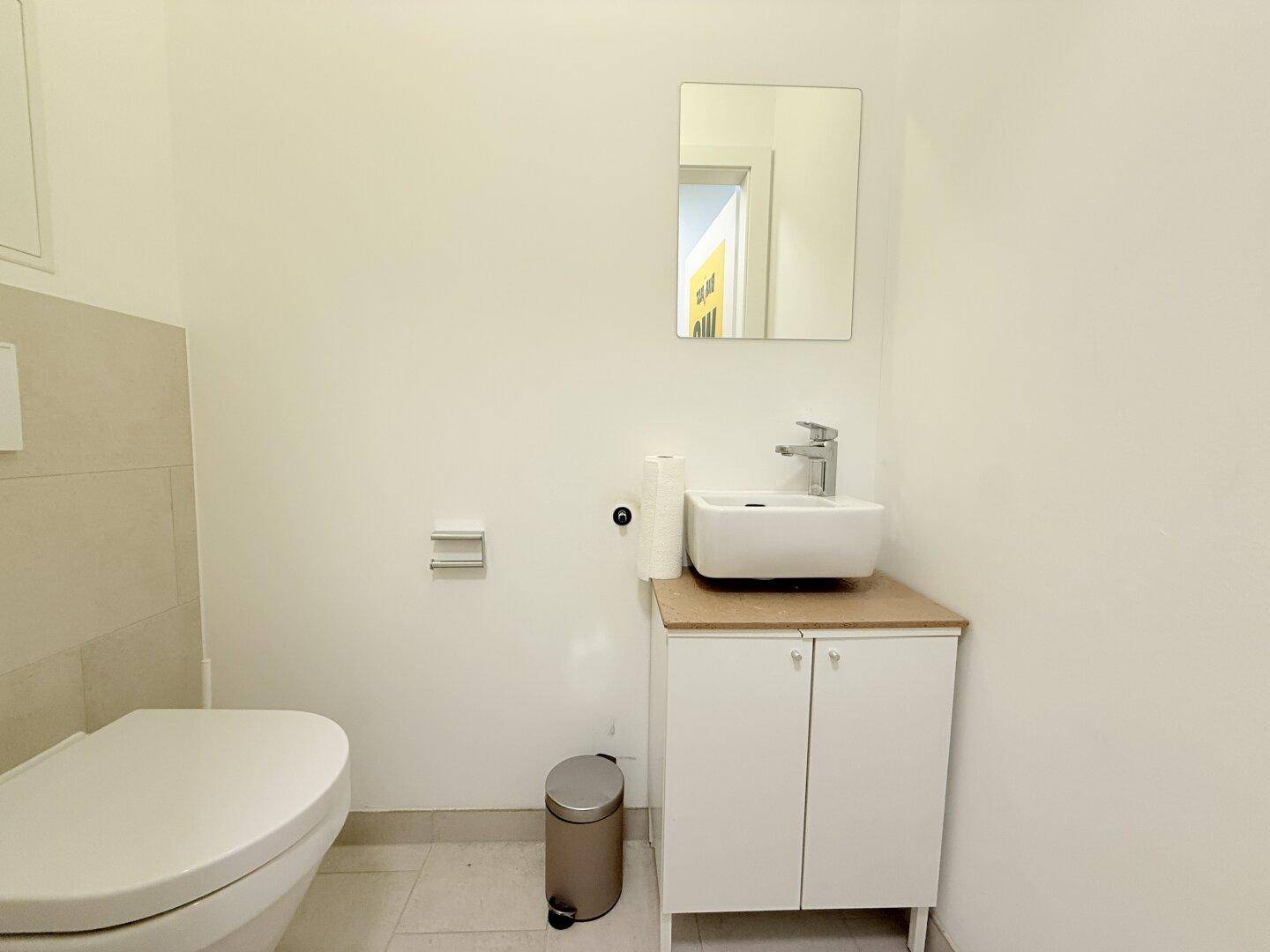 Kleines Gäste-WC mit wandhängender Toilette und einem modernen Aufsatzwaschbecken.