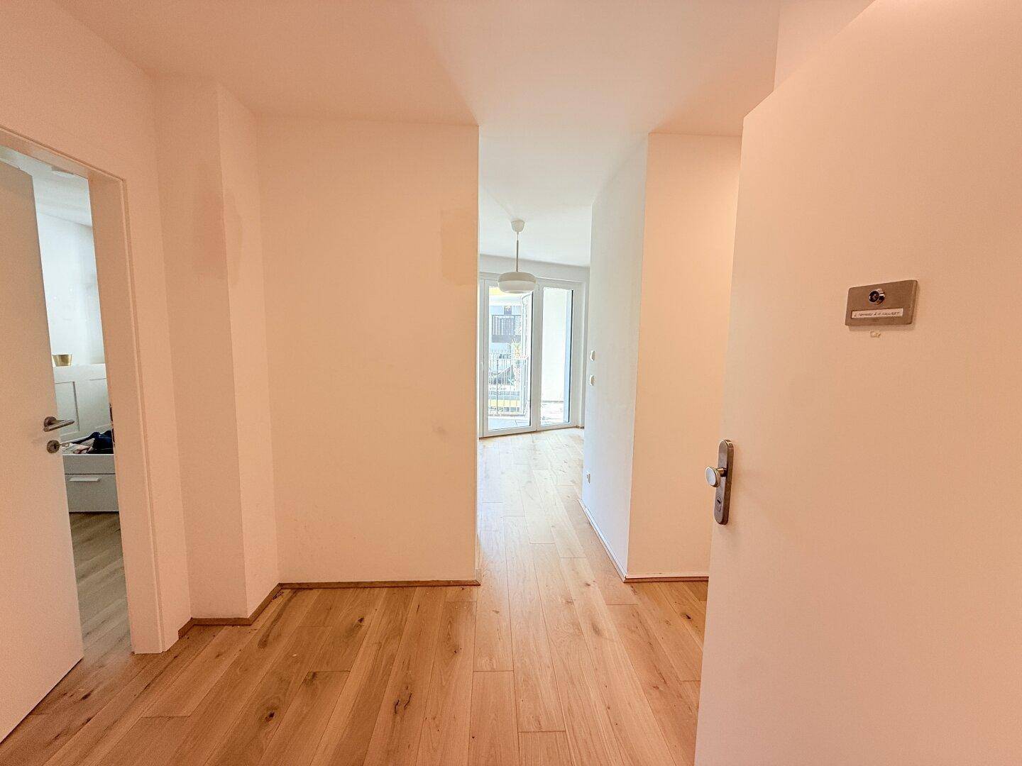 Heller Flur mit Parkettboden, der zum offenen Wohnbereich der Wohnung führt.