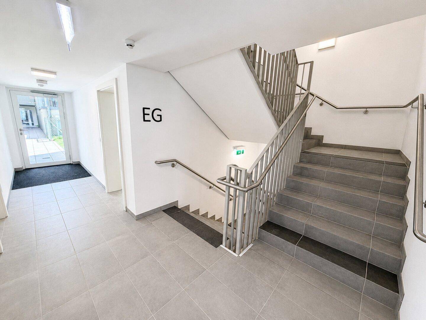 Heller Eingangsbereich mit Treppenhaus und Fliesenboden, der zu den verschiedenen Etagen führt.