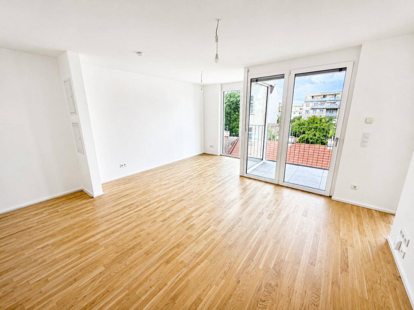 Geräumiges, helles Wohnzimmer mit Parkettboden und Zugang zu einem Balkon, ideal für entspannte Stunden.