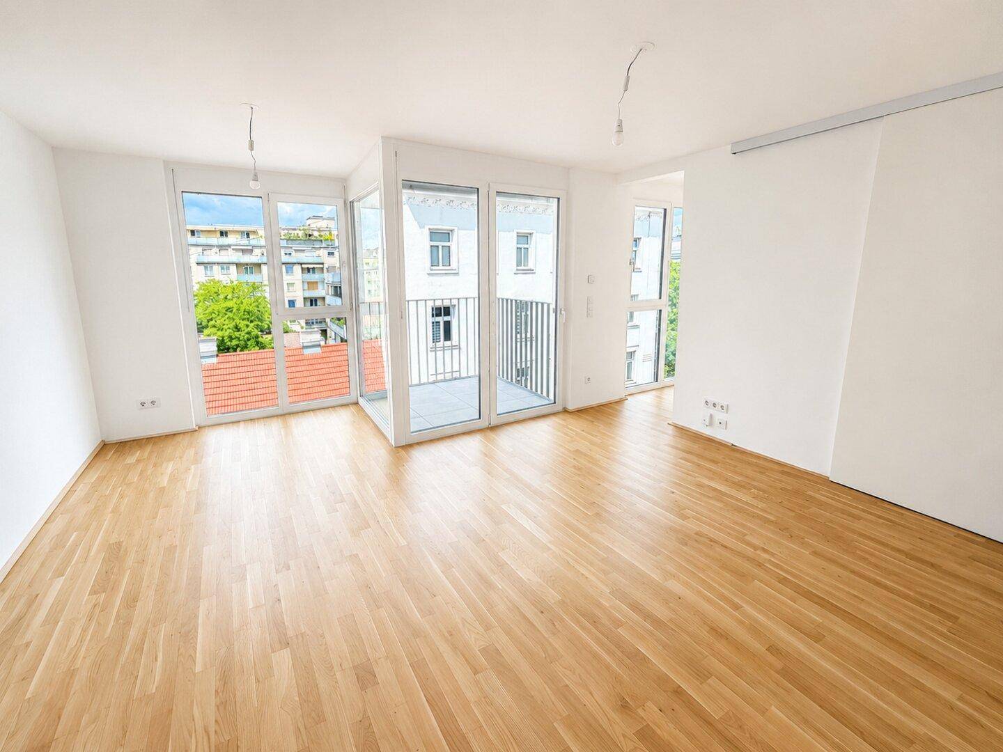 Helles Wohnzimmer mit Eichenparkettboden und großen Fenstern, die viel Tageslicht hereinlassen.