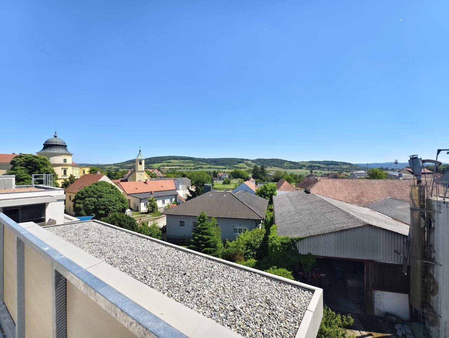 Panoramablick über die ländliche Umgebung mit historischen Gebäuden und grünen Hügeln.