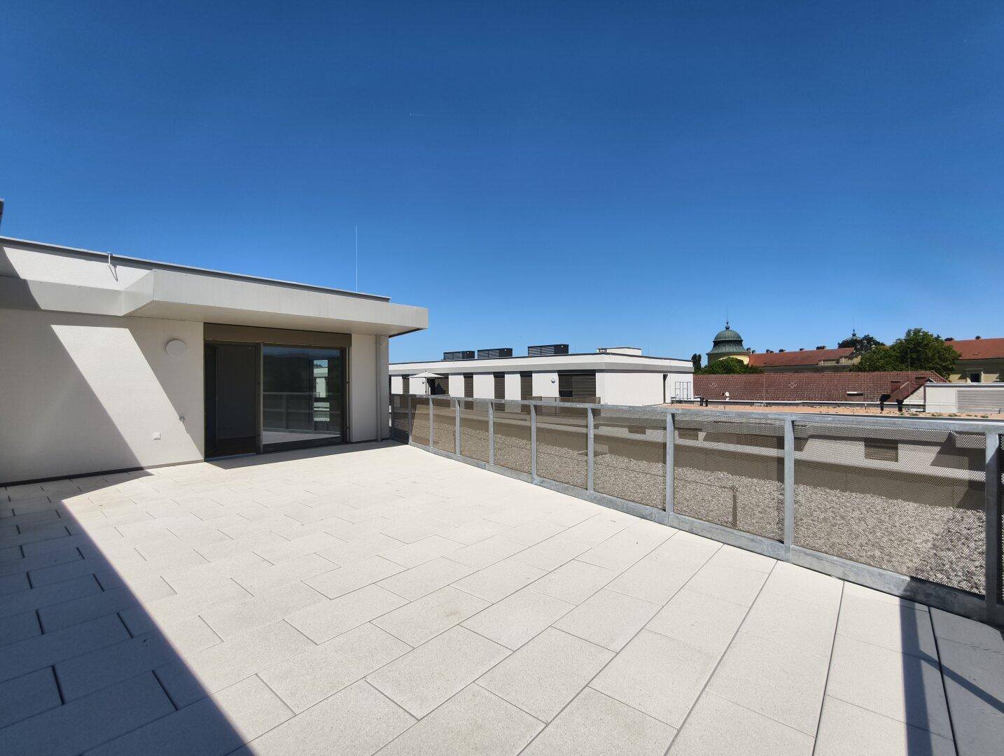 Geräumige Dachterrasse mit modernem Geländer und Zugang zu den Innenräumen des Neubaus.