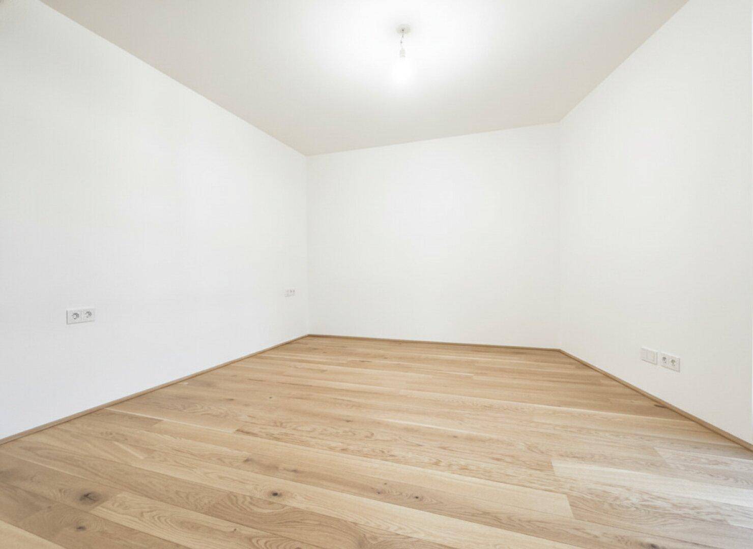 Leeres Zimmer mit Holzdielenboden und weißen Wänden, bietet vielseitige Nutzungsmöglichkeiten.