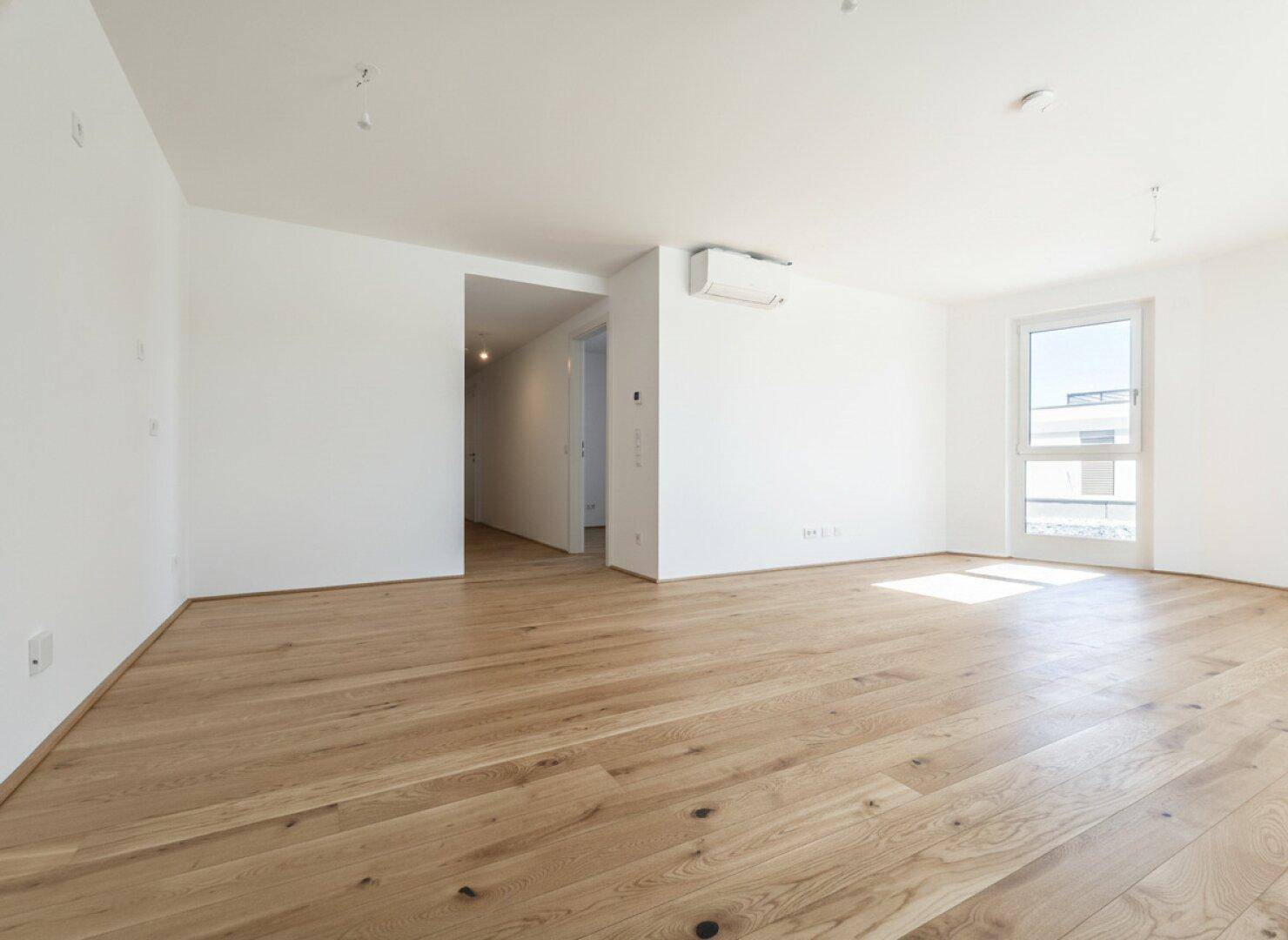 Geräumiges, helles Zimmer mit Holzdielenboden und Klimaanlage, bereit zur individuellen Gestaltung.